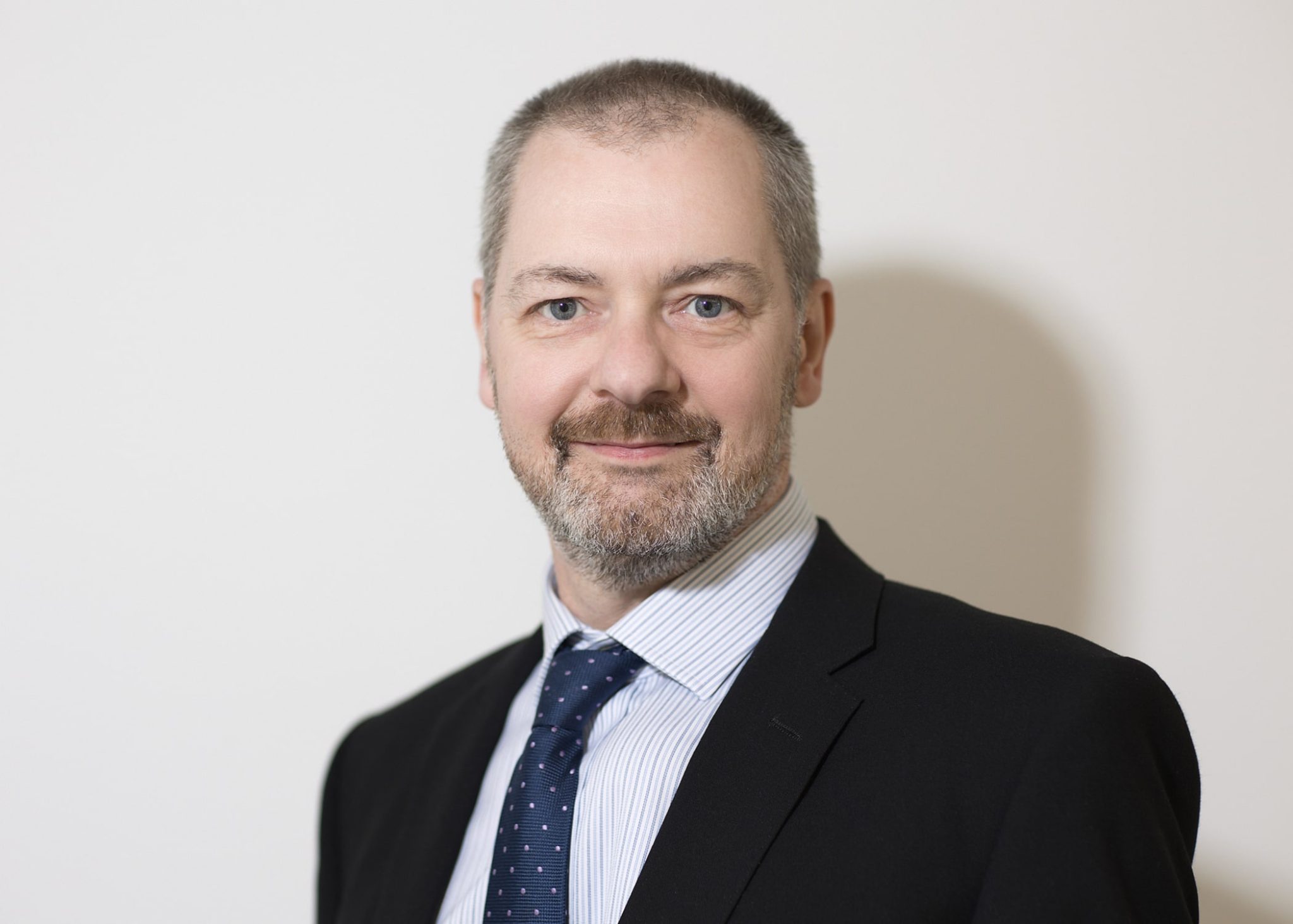 A headshot image of Alistair Duncan wearing a suit and tie.