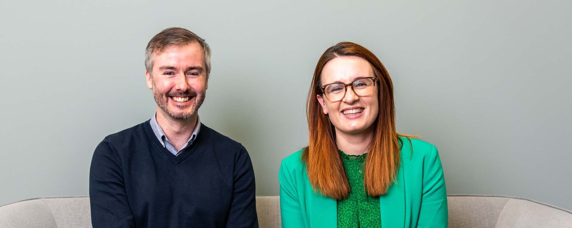 Two AAB employee sitting next to one another on sofa.