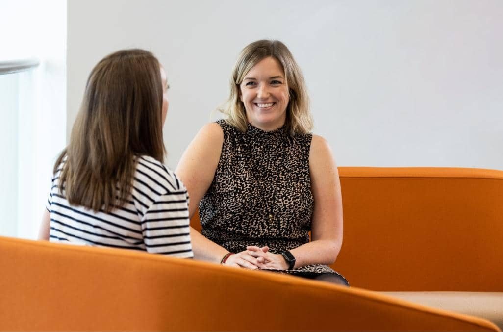 Two people laughing on a sofa.