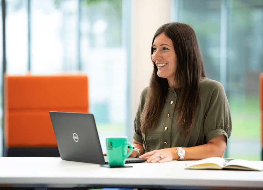 AAB team member sitting smiling on laptop.