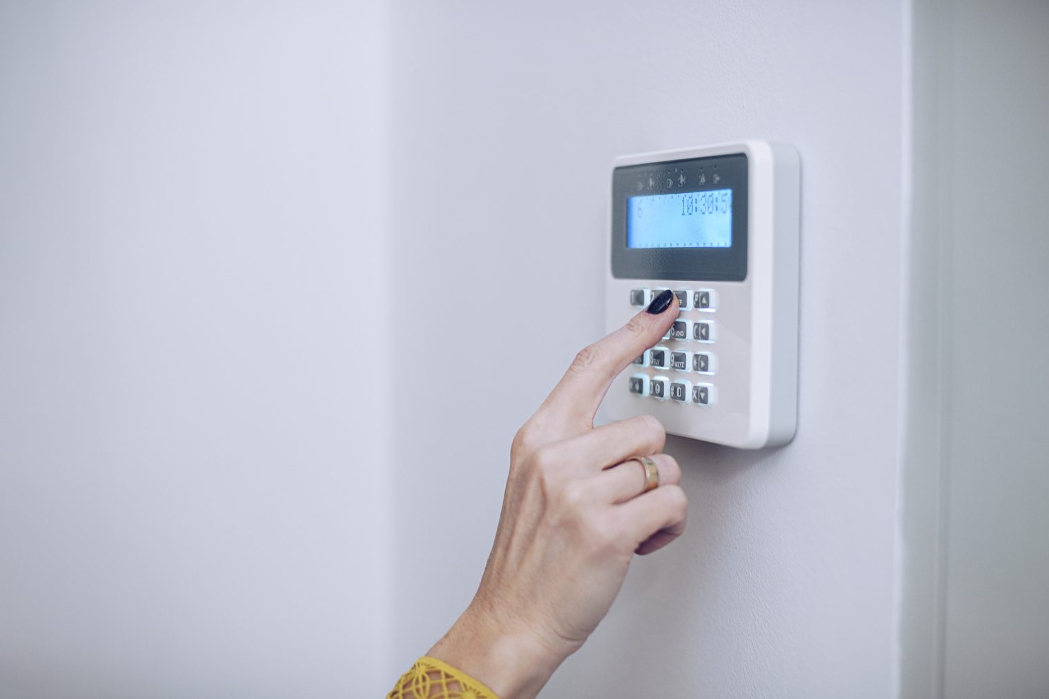 A hand pressing a keypad on a wall