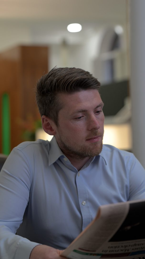 An image of Patrick Lynch sitting in the office and reading a newspaper.