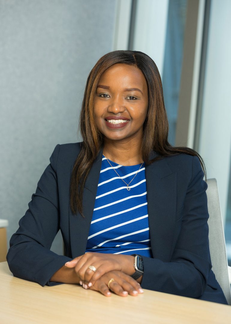 Linet Kiilu sitting at a desk with her hands crossed smiling at the camera