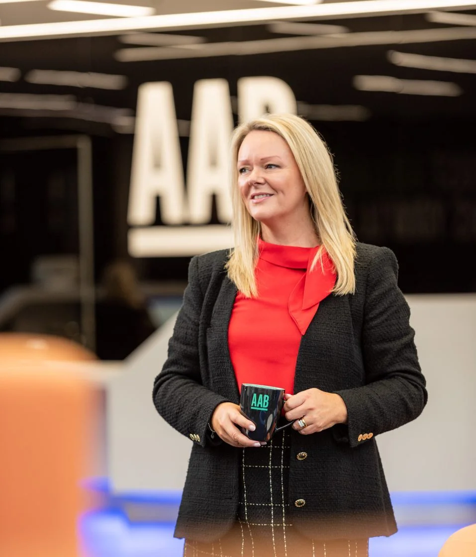 Woman standing with coffee mug in AAB office.