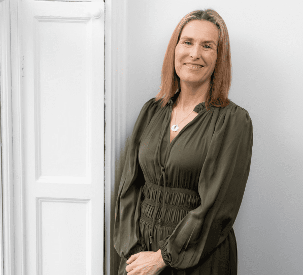 An image of Sylvia Stanbridge wearing a green dress and smiling at the camera.